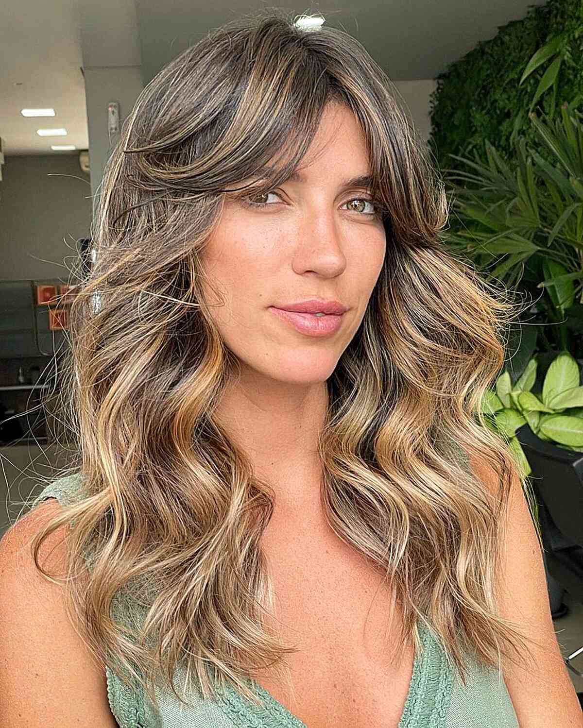 Thick Long Curtain Bangs on Medium-Length Wavy Hair with Blonde Balayage